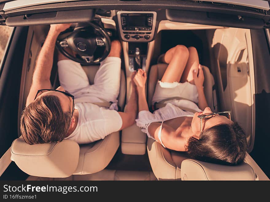 High-angle photo of adorable cute husband wife wear white outfits riding automobile holding arms outside urban city route.