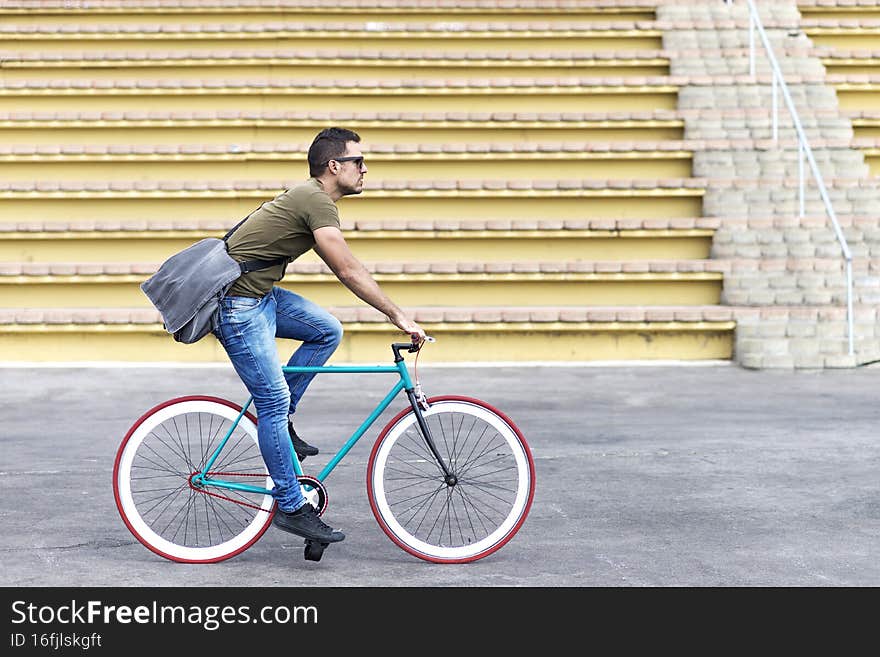 Male with sunglasses riding bicycle in urban city commuting trendy transportation