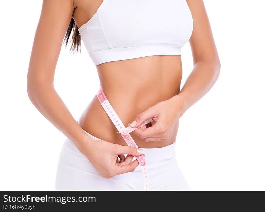 A perfect waistline. Cropped studio shot of a fit young woman taking her measurements  on white.