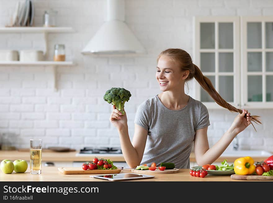 Vegetable food and diet - home lifestyle portrait smiling cheerful woman at domestic kitchen with broccoli. Stay healthy