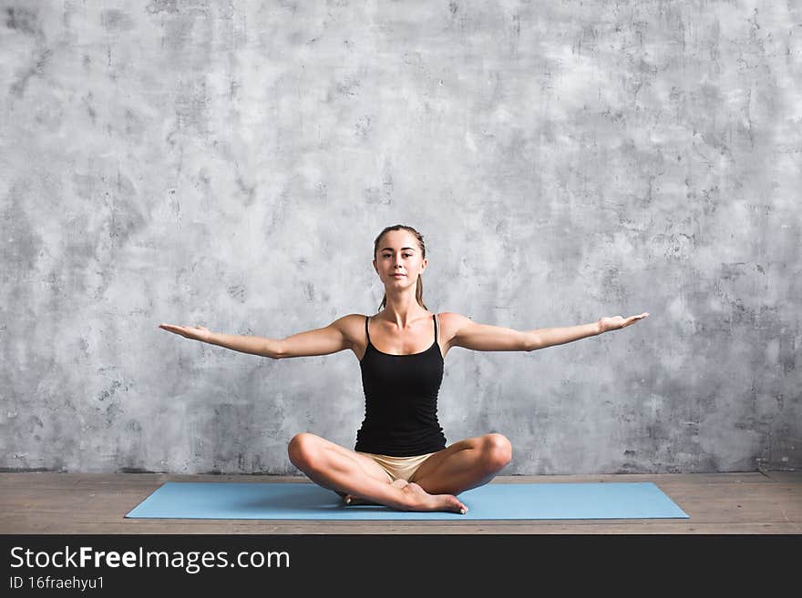 Beautiful woman in lotus position on a blue mat indoors doing yoga, stay healthy