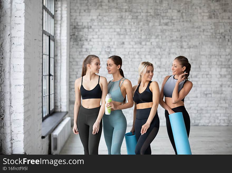 Group smiling women with yoga mats after training in fitness studio. Healthy active lifestyle, working out