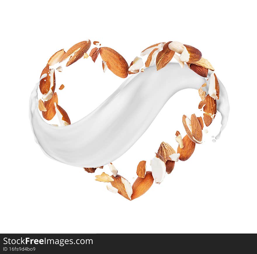 Crushed almonds in the air in the shape of a heart with milk splashes, isolated on white background.