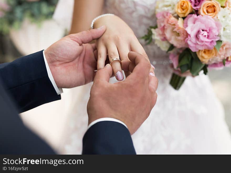 The groom puts the ring on the bride& x27;s finger in close-up.
