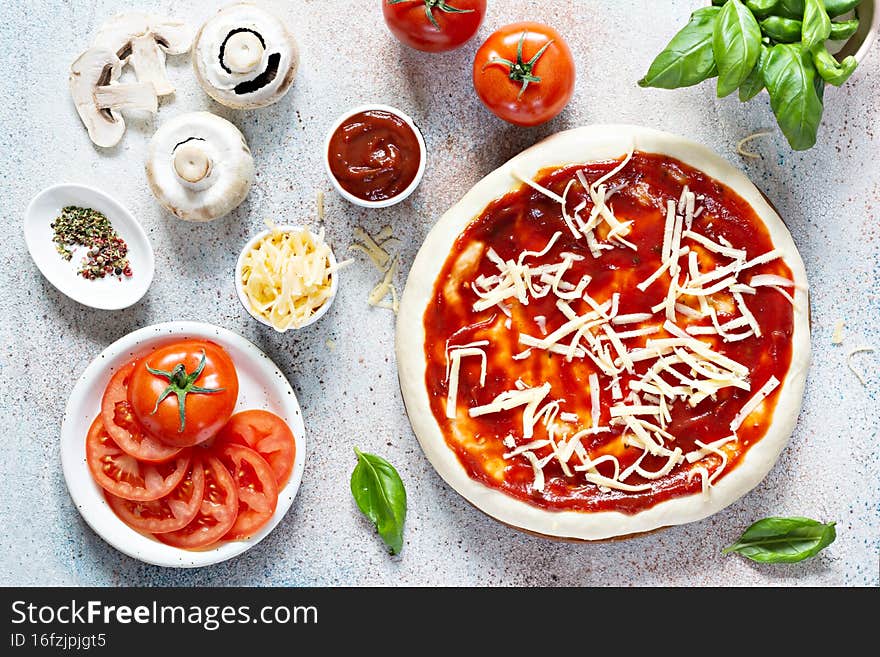 Cooking Italian pizza with tomato sauce, fresh tomatoes, cheese, mushrooms, salami slices and basil .