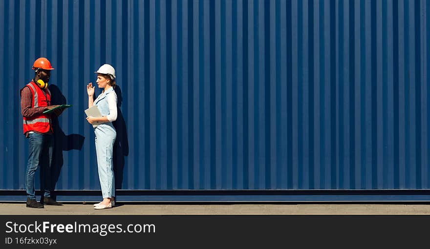 Businesswoman and engineer talking and checking loading Containers box from Cargo freight ship for import export. shipping in docks
