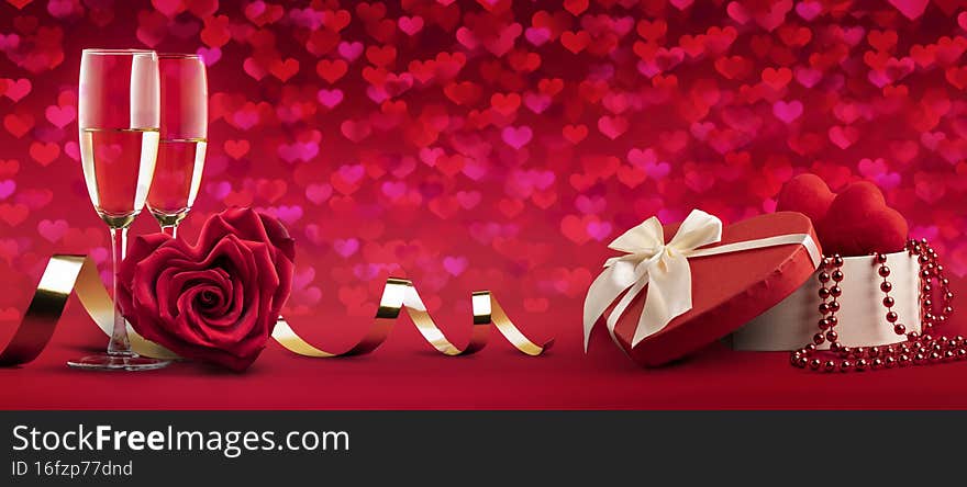two glasses of champagne wine, a rose in the shape of a heart and a box with gifts for the wedding day or happy