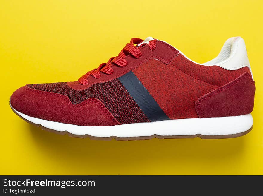 New unbranded running sneaker or trainer on yellow background. Men`s sport footwear