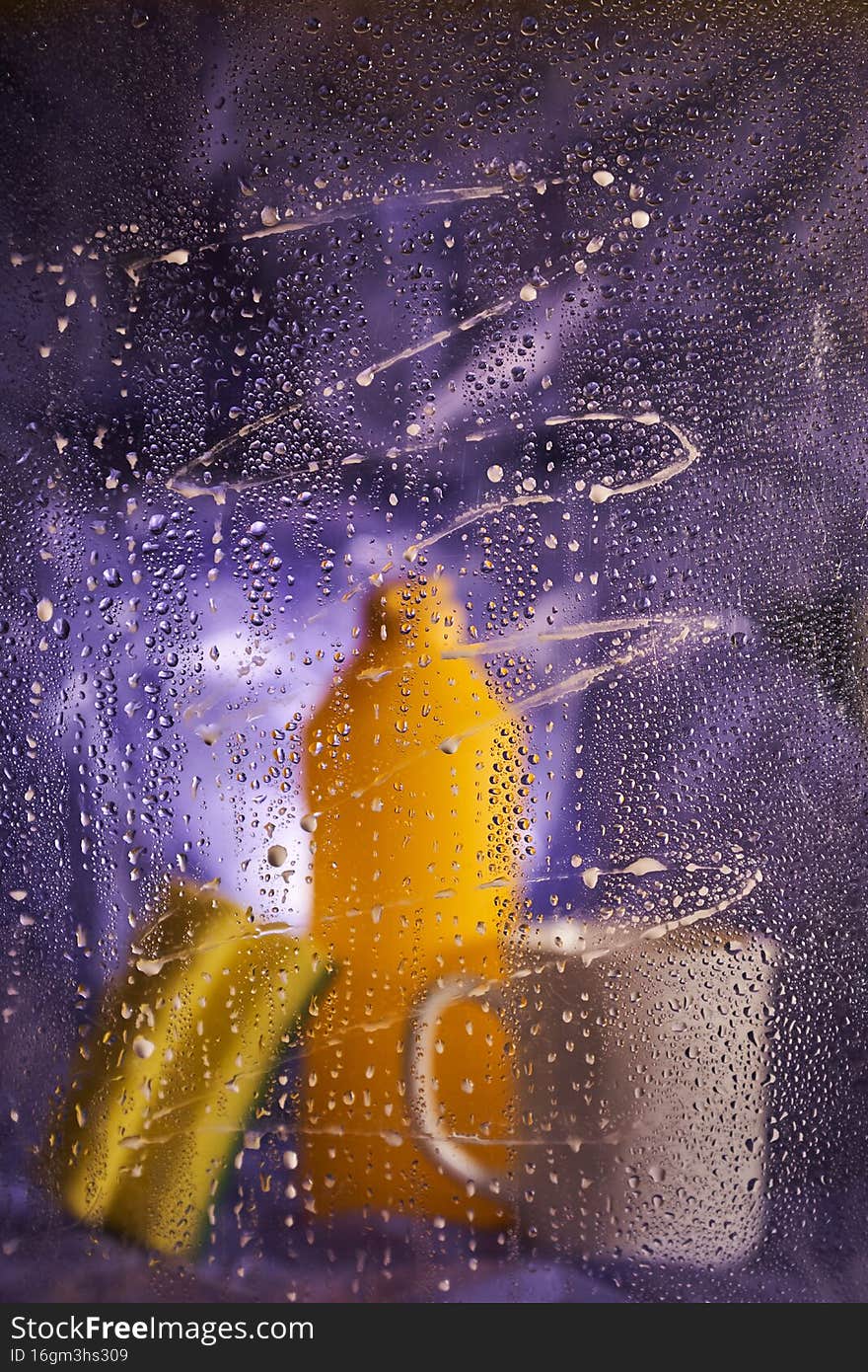 View through dirty glass. Close-up of household cleaning products and kitchen accessories. On a dark lilac background. High quality photo