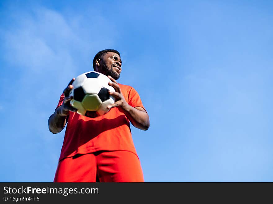 happy multicultural hispanic soccer player smiling and wear red sporty suit outdoor sunny day