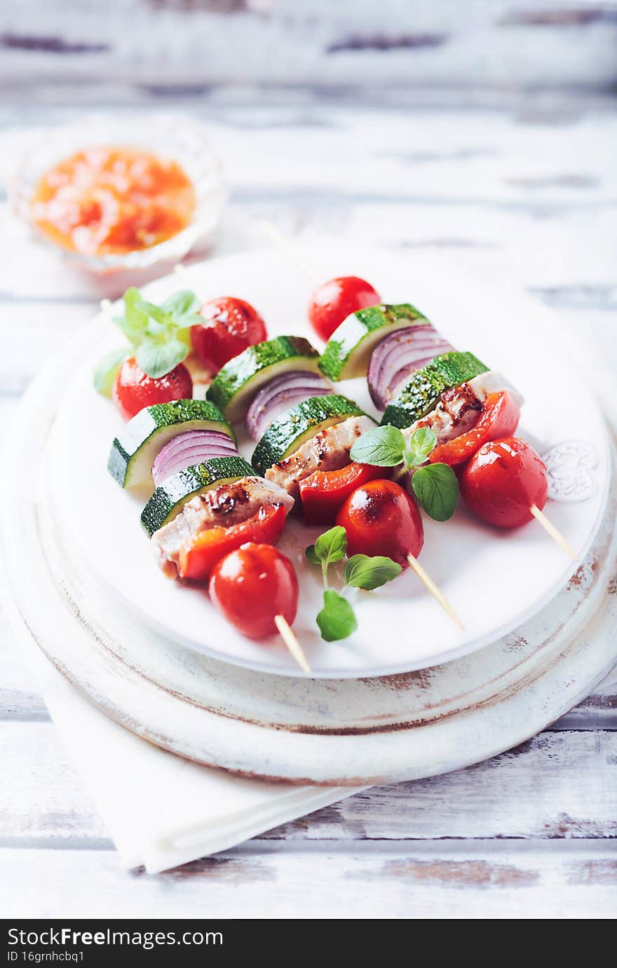 Grilled shashliks with vegetables and pork tenderloin. Bright wooden background. Close up.