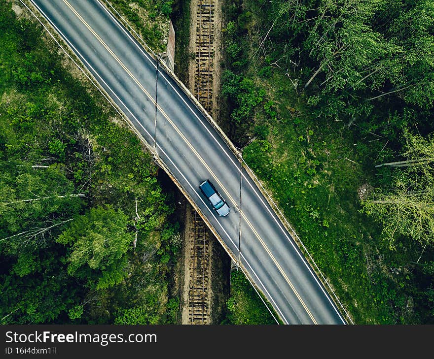 Aerial view of country road above the railway in a green summer forest