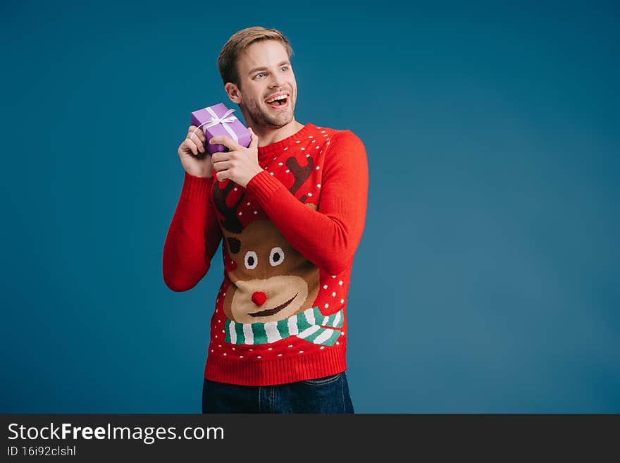happy man in sweater holding christmas present isolated on yellow,stock image