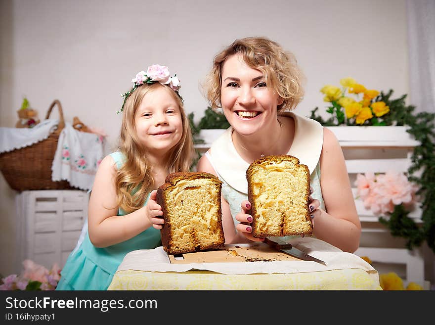 Nice mom and beautiful blonde daughter in room durin spring photo shoot before easter with festive bread, kulesh or cake