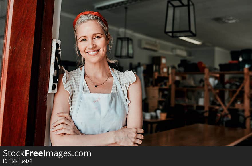 Please, come in. Cropped portrait of an attractive mature woman standing with her arms folded in her pottery workshop.