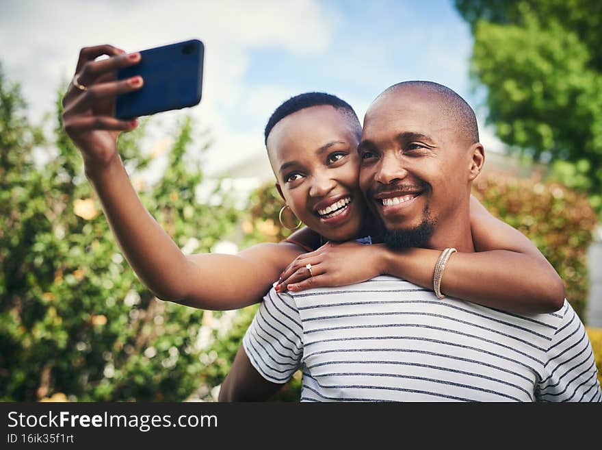 Share your happiness with the world. Cropped shot of a happy young couple taking a selfie outside.