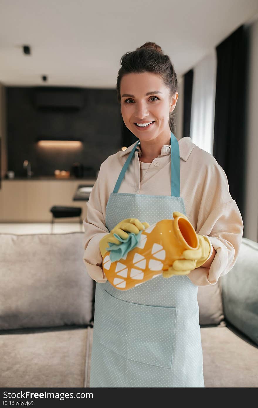 Cleaning crockery. A woman in gloves cleaning an orange vase
