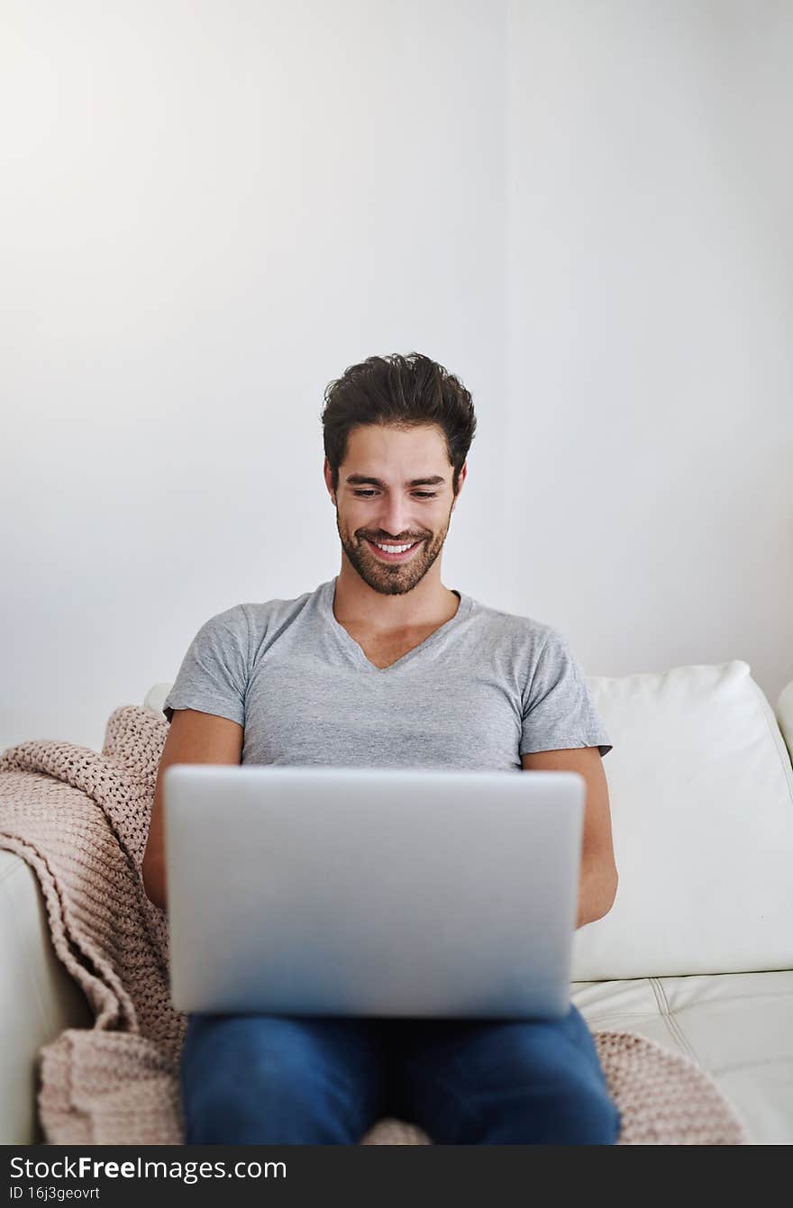 Shot of a young man browsing the internet at home on a laptop. Shot of a young man browsing the internet at home on a laptop