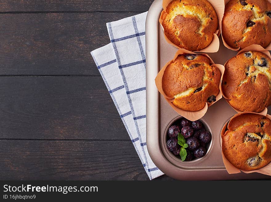 A group of mafins with berries and chocolate on a dark wooden background. FLat lay.
