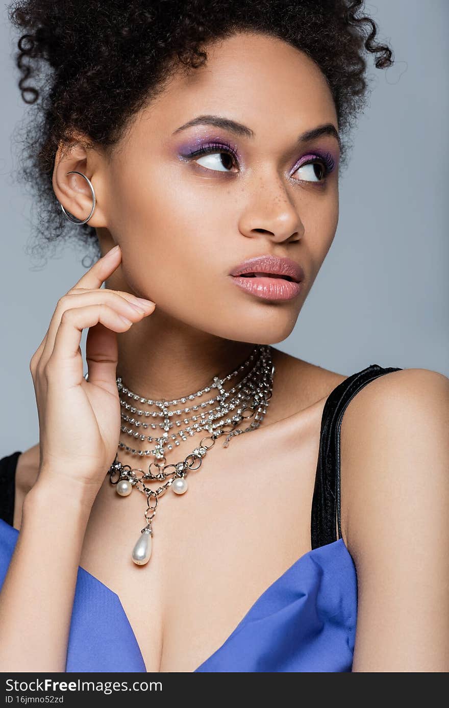 pretty african american woman with purple eye shadow isolated on grey,stock image