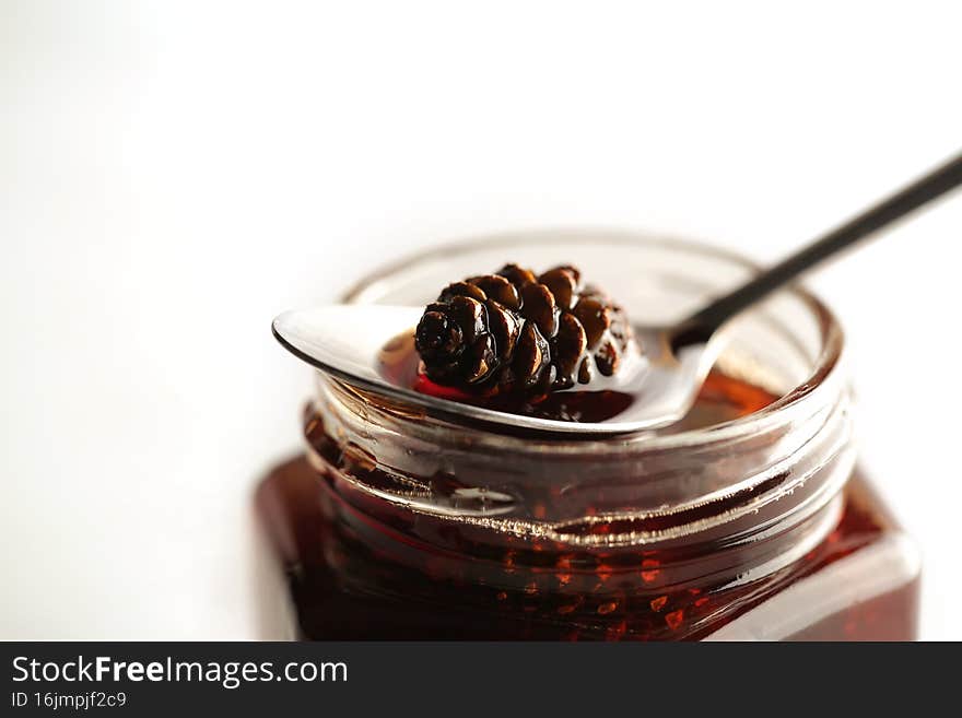 Jam with small fir cones is on the kitchen table in a glass jar. Jam with small fir cones is on the kitchen table in a glass jar