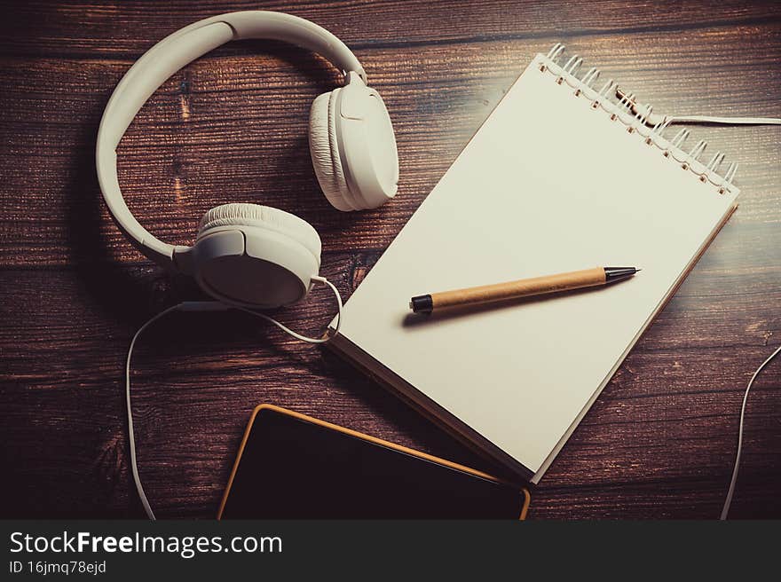 Notepad, headphones and phone on the table for work and creativity. Notepad, headphones and phone on the table for work and creativity