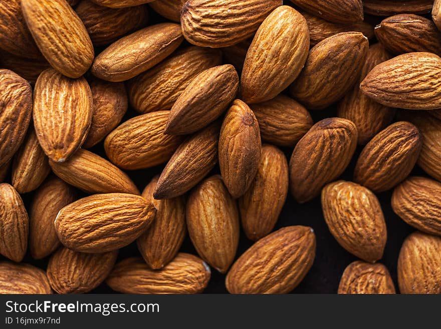 Close up raw almonds on dark wooden table. Selective focus. Organic health protein vegetarian food concept. Snack contains vitamins and minerals. Background. Close up raw almonds on dark wooden table. Selective focus. Organic health protein vegetarian food concept. Snack contains vitamins and minerals. Background