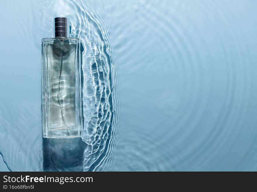 Perfume bottle on blue water wavy background. Fresh sea fragrance concept. Pure and chilly. Copyspace