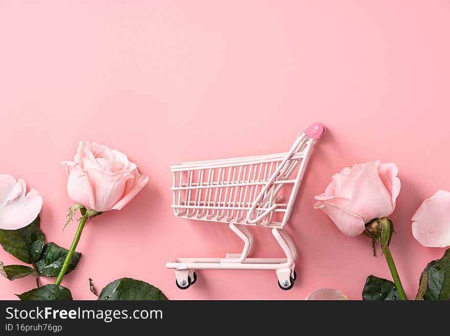 Valentine`s Day shopping design concept background with pink rose flower and cart on pink background