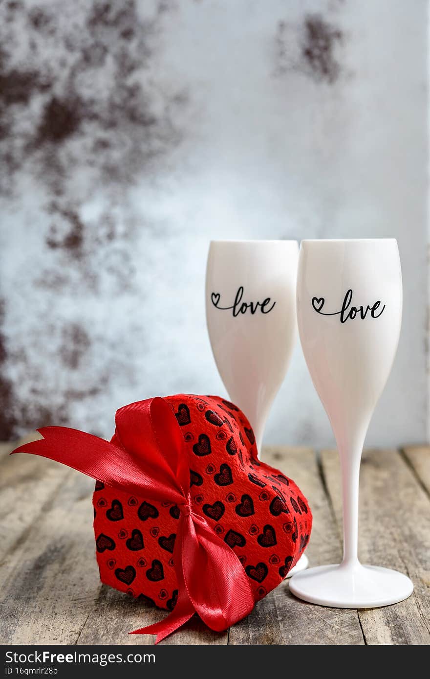 Valentine`s Day concept. Two glasses for champagne and heart shaped gift box on a wooden table. Selective focus. Valentine`s Day concept. Two glasses for champagne and heart shaped gift box on a wooden table. Selective focus