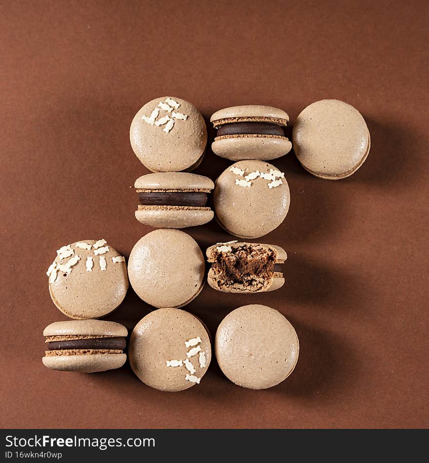 Some perfect brown macarons cakes against a monochromatic brown background.