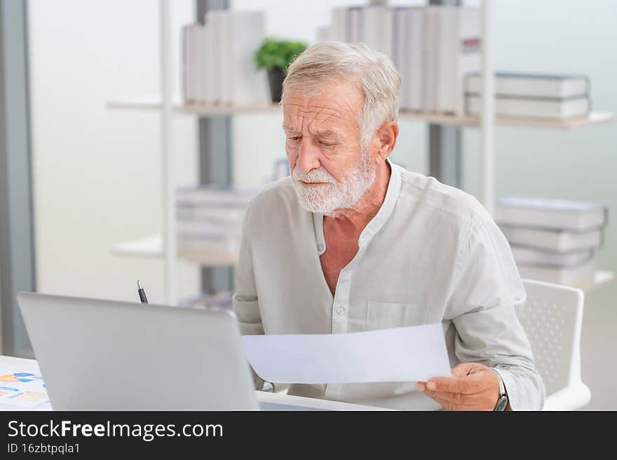 Worried senior man checking their bills, retired elderly old family reading documents, Mature man in living room with laptop.