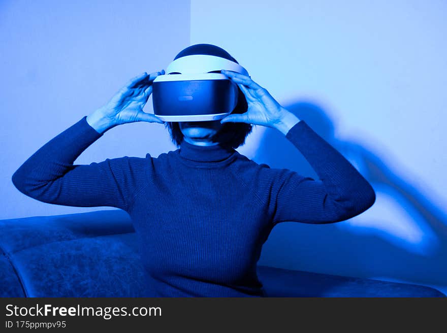 Beautiful woman using vr headset in virtual space at home in blue light. The concept of the virtual universe. Lifestyle in the virtual space