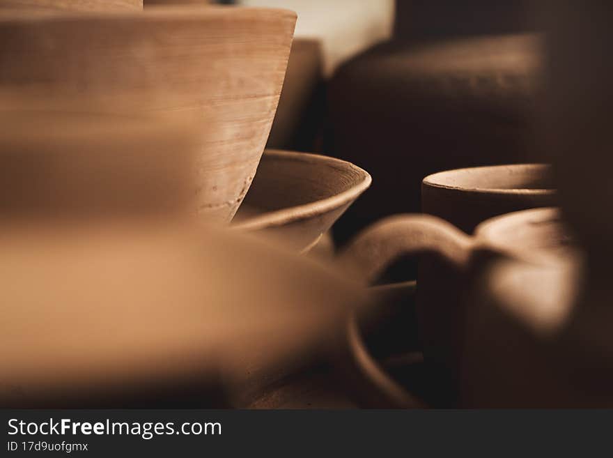 Shelves with bowls, plates, jars, teapots, etc. made in clay in natural raw color until the final painting. Crafts in clay. Close-up
