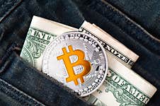 A Silver Physical Bitcoin Coin With Golden Symbol B And Folded American Dollars. Royalty Free Stock Images