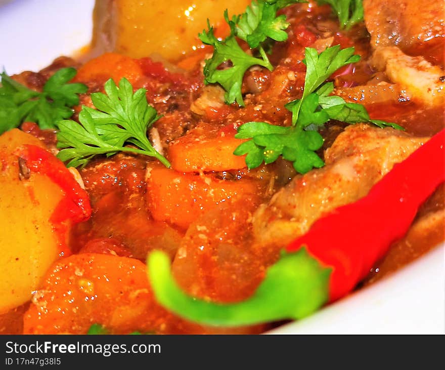 Beef goulash with potatoes, beef, tomato sauce, parsley and hot peppers