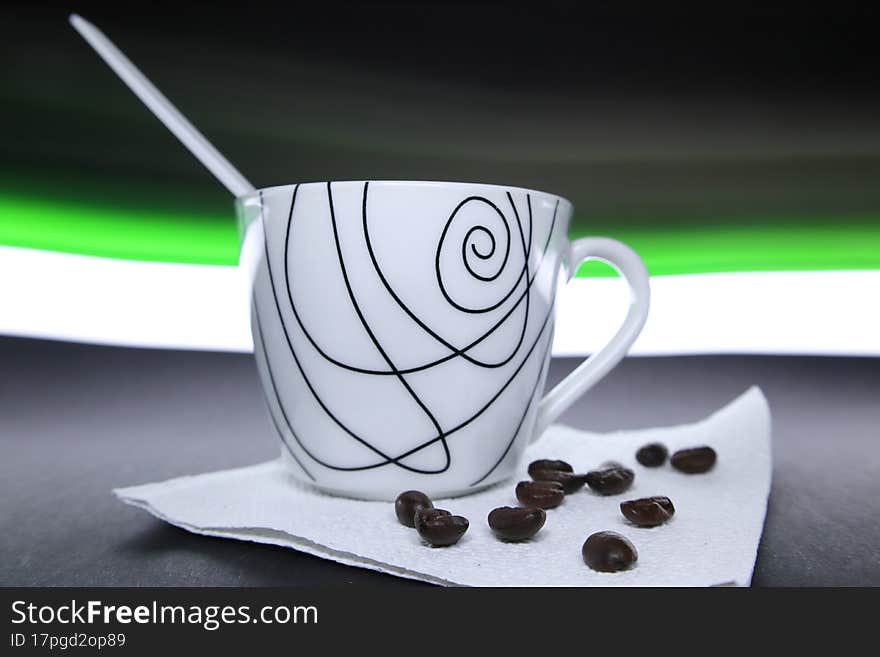 Coffee cup with beans next to it and green and white light in the background