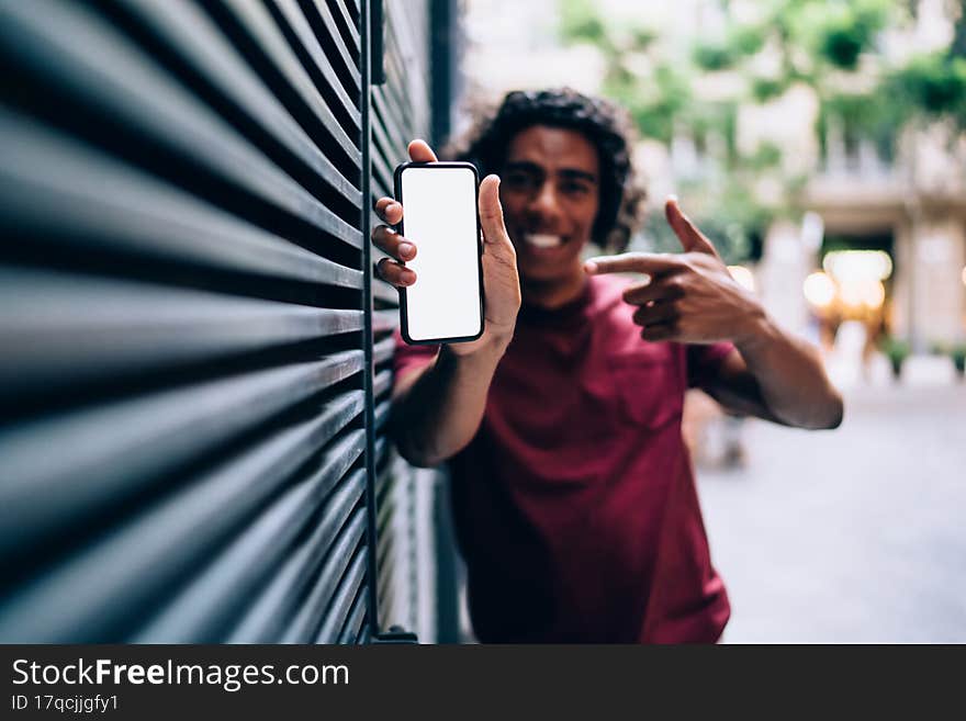 Blurred man with blank cellphone pointing on mock up screen display with copy space area for social publication with advertising. Blurred man with blank cellphone pointing on mock up screen display with copy space area for social publication with advertising