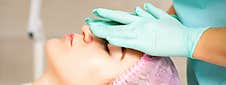 Cosmetologist With Gloved Hands Applies A Moisturizing Mask With Peeling Cream On The Female Face. Facial Cosmetology Stock Image