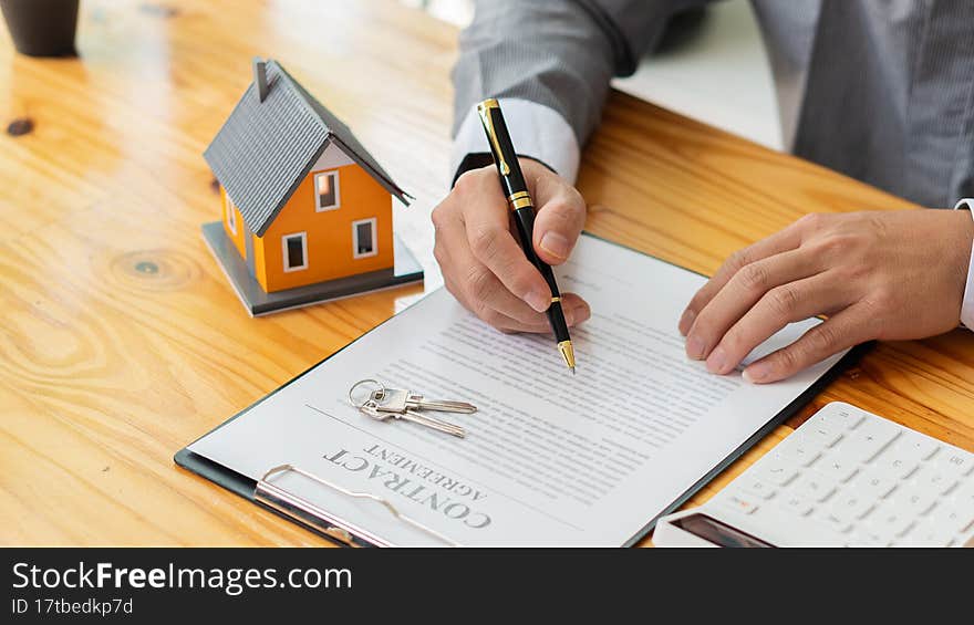 Businessmen holding pens, signing home titles with insurance, care about real estate services and the idea of real estate agents offering interest in installments to their customers...