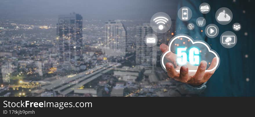 Global communication network concept, Person hand holding 5G icon on virtual screen with city scape background, World wide business, high-speed mobile Internet, new generation networks. Mixed media