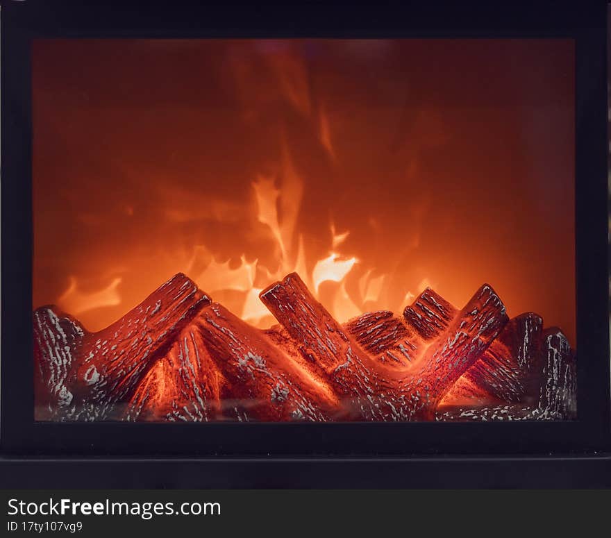 Fireplace with bright flames. Artificial decorative fireplace with imitation of fire. Modern technology for warmth and home comfort. Front view.