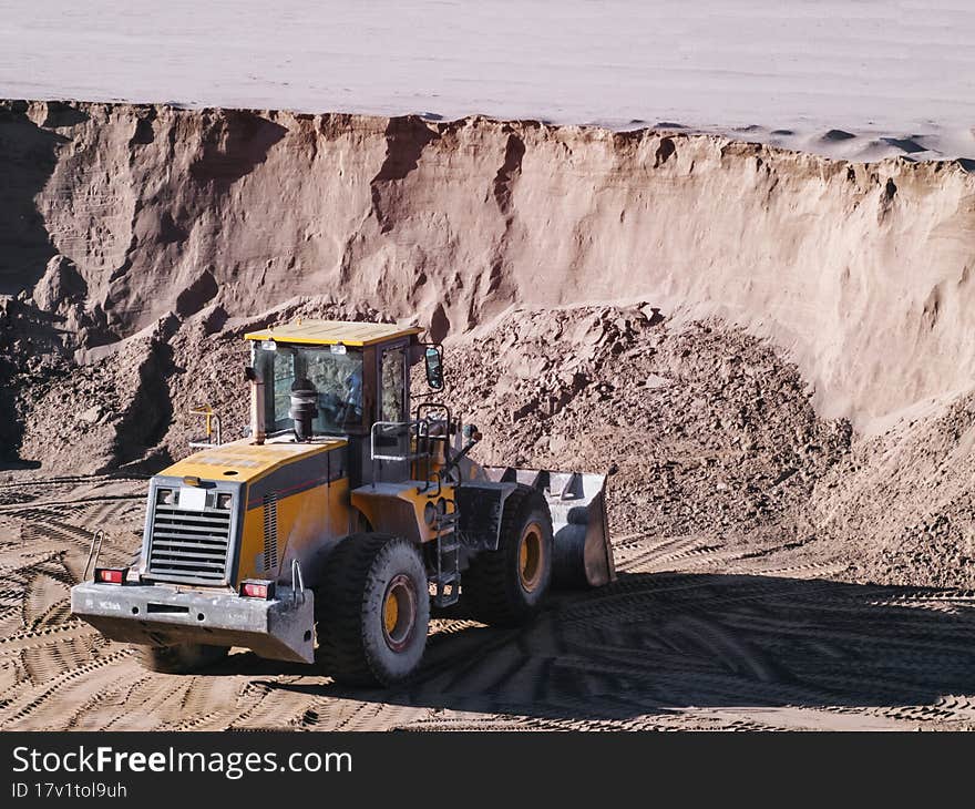 Tractor with a bucket in a sand pit.