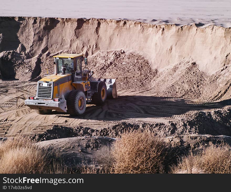 Tractor loader in front of the sand layer.