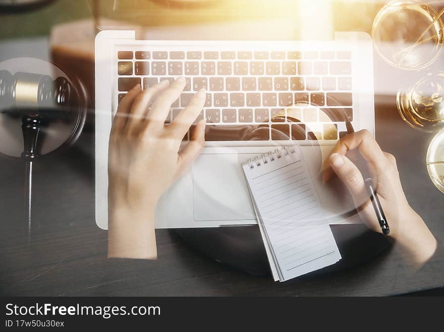Justice and law concept.Male judge in a courtroom with the gavel, working with, computer and docking keyboard, eyeglasses, on table in morning light