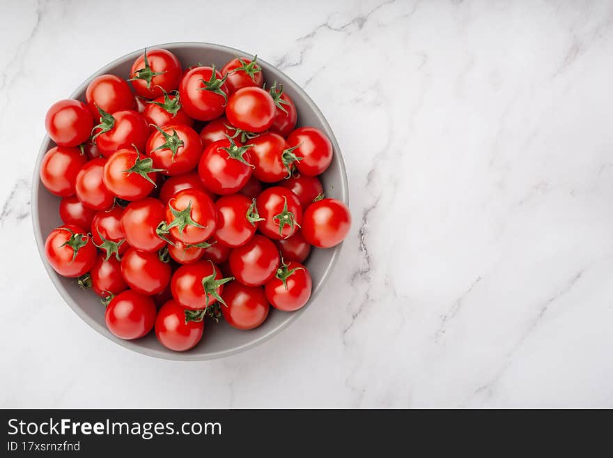 plate with cherry tomatoes on white marble background