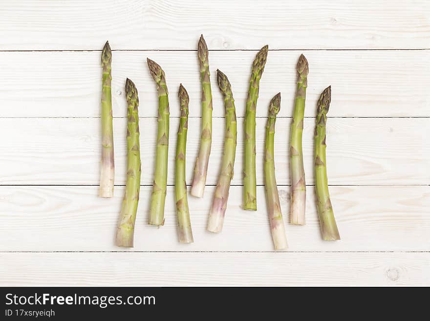 Asparagus stems on white wooden table. Top view