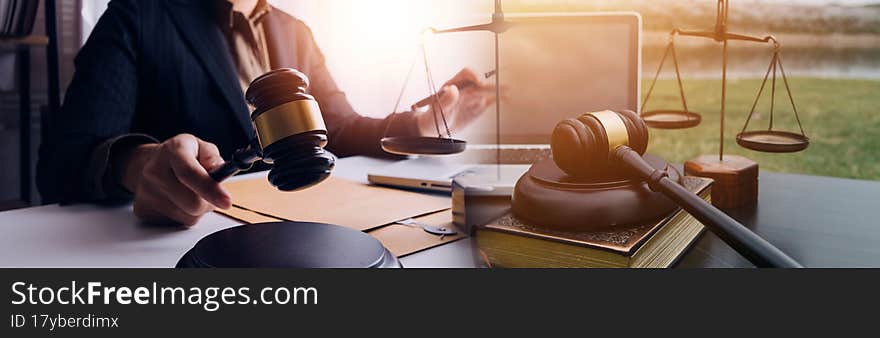Justice and law concept.Male judge in a courtroom with the gavel, working with, computer and docking keyboard, eyeglasses, on table in morning light