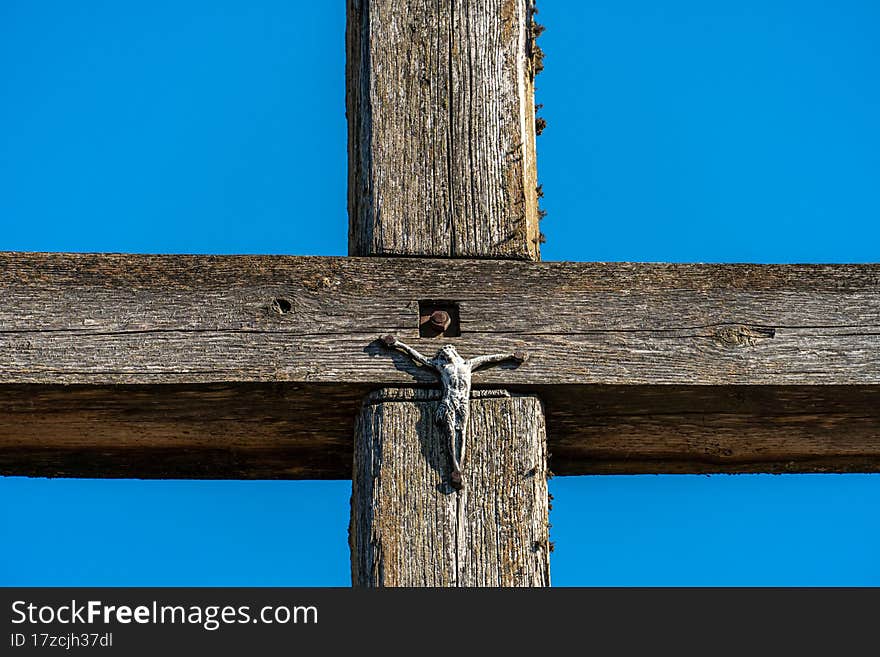 An Old Wooden Cross Against A Clear Blue Sky. The Crucified Jesus On The Cross. The Concept Of The Pure And Unrequited Love Of God