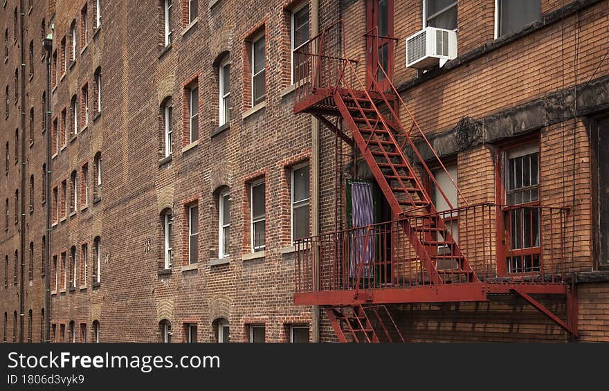 Red fire escape and row of connected red brick buildings. Red fire escape and row of connected red brick buildings